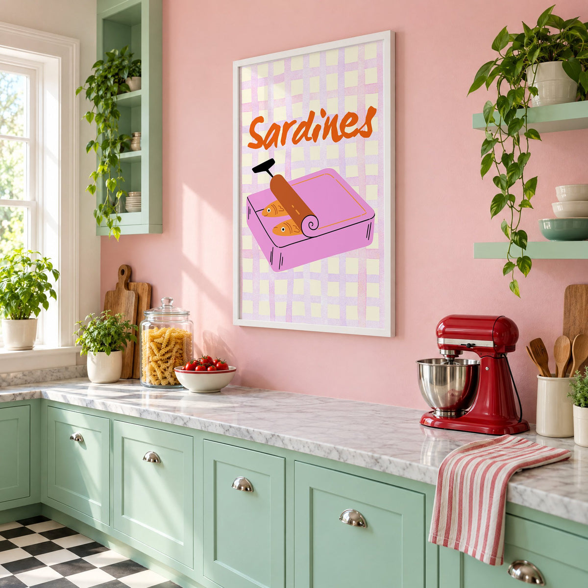 Sardines pink tin on gingham print in a white frame on a pink wall above mint green cabinets in a retro kitchen, seen at an angle