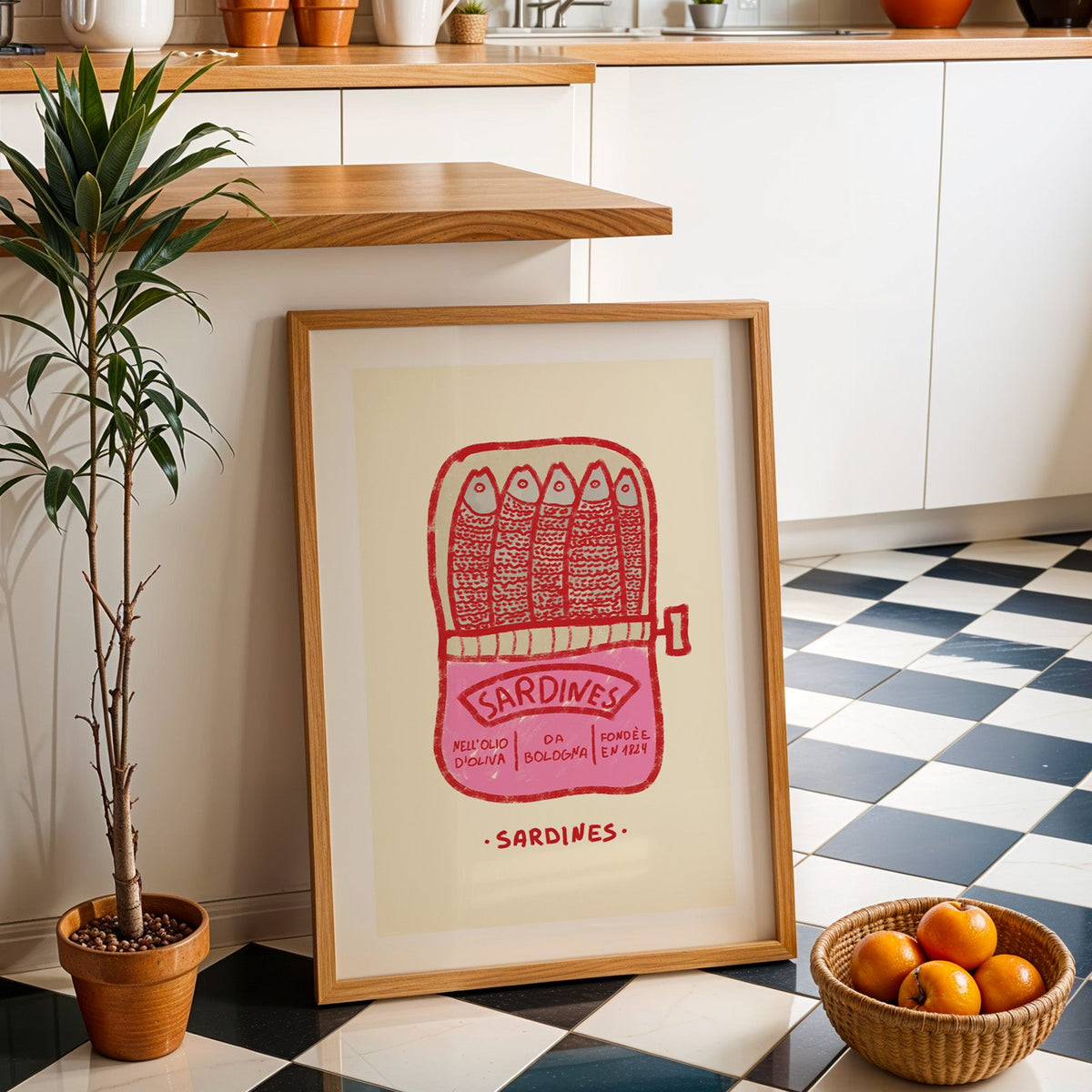 Pink sardine tin print in an oak frame by a kitchen island and checkered floor
