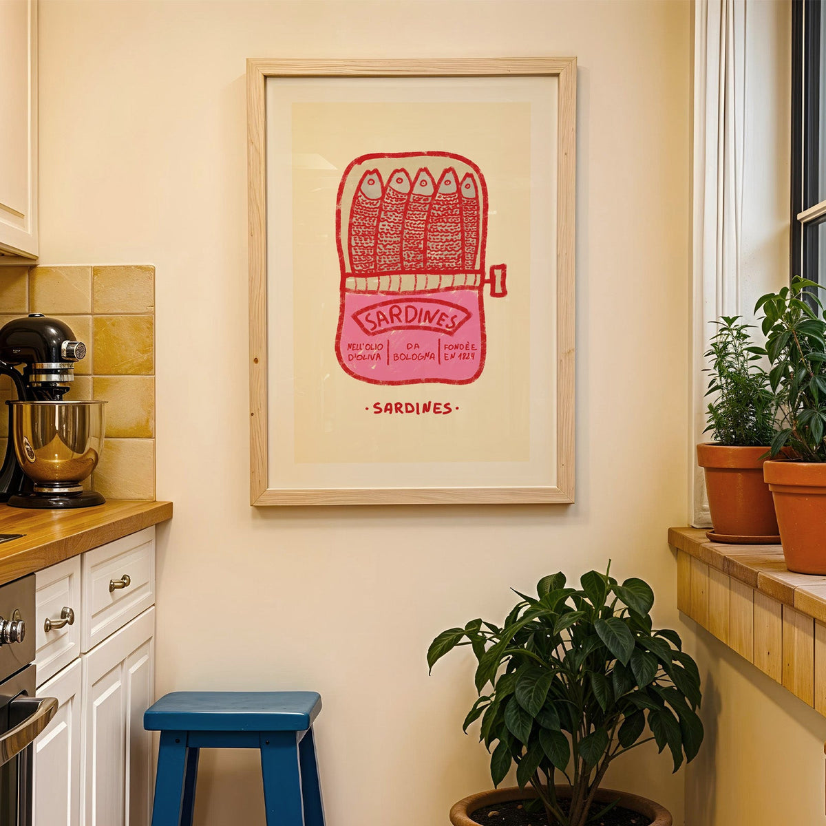 Pink sardine tin print in a wood frame on a yellow tiled kitchen wall