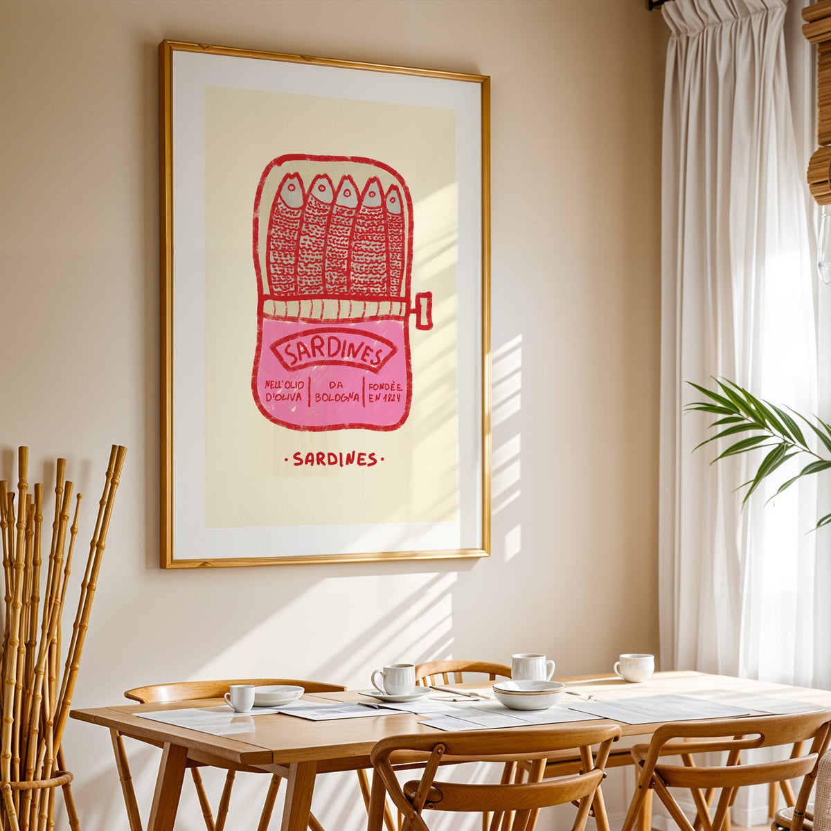 Pink sardine tin print in a gold frame above a sunlit breakfast table
