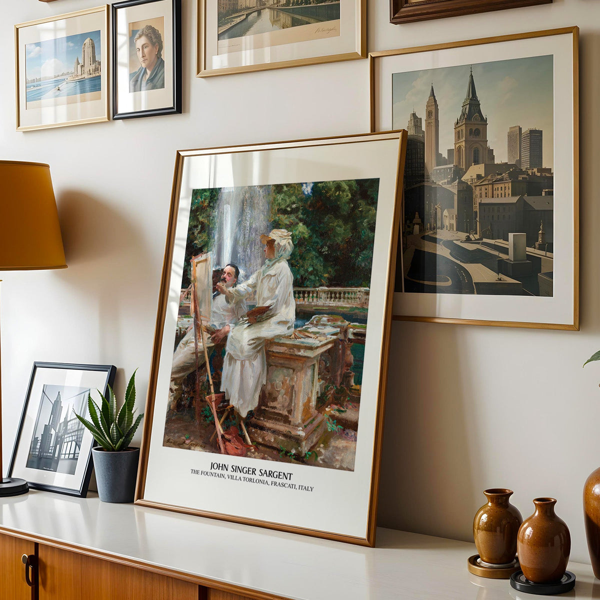 Impressionist garden print shown in a gold frame leaning on a sideboard in a gallery wall