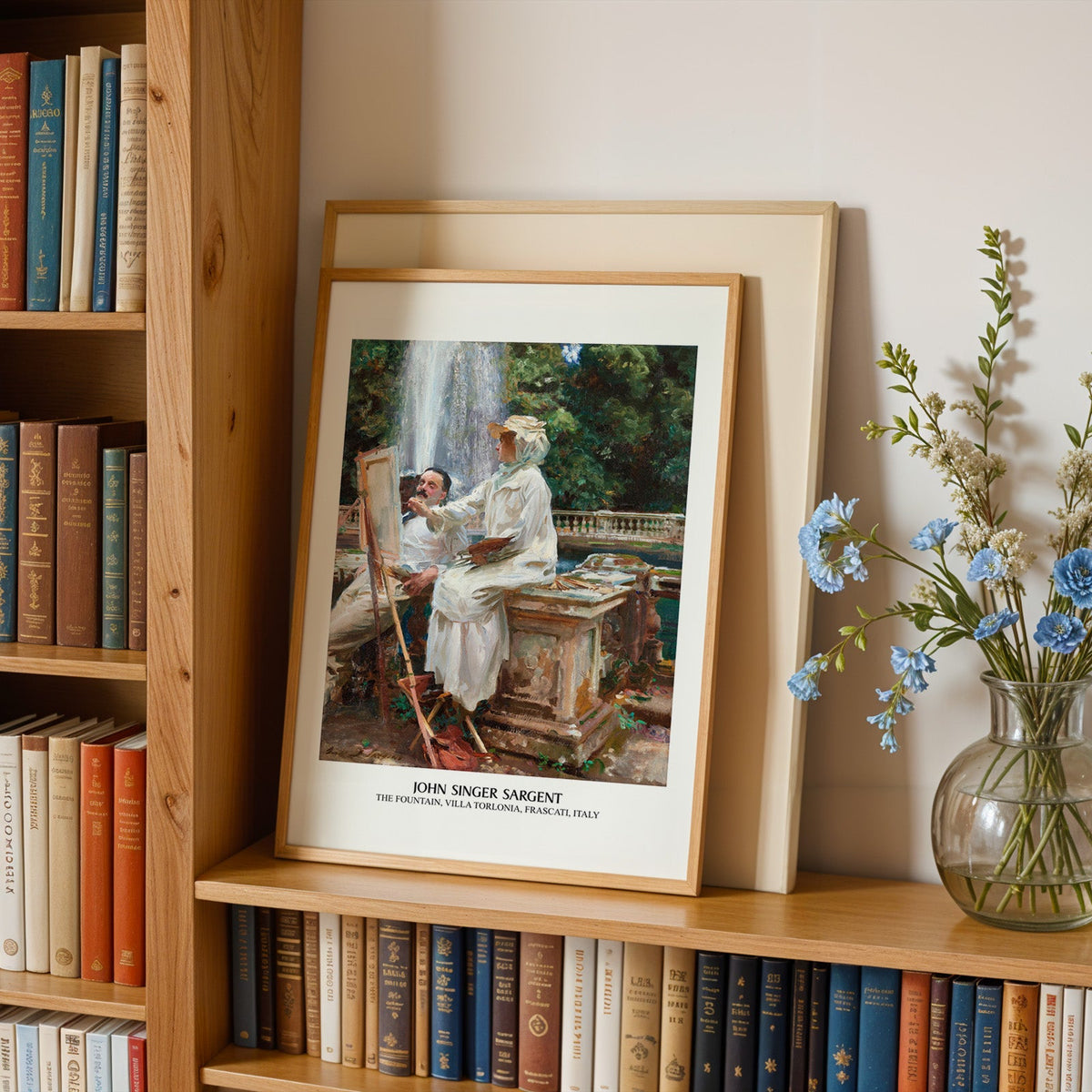 Frascati fountain painting print in an oak frame leaning on a bookshelf beside flowers