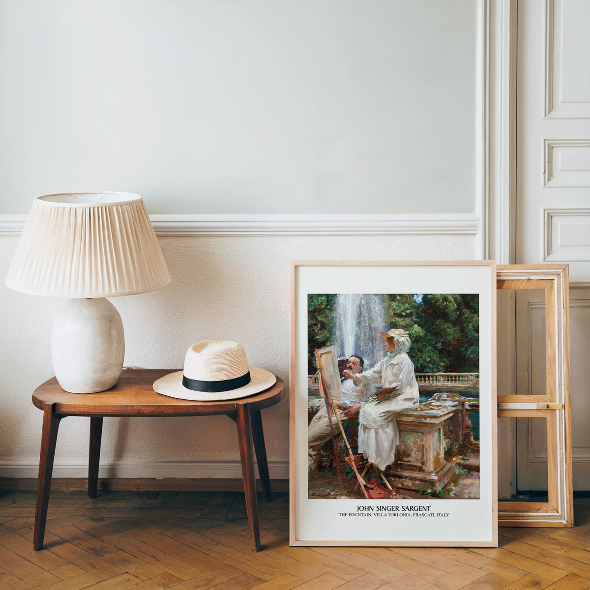 Summer garden poster in a light wood frame leaning by a bench and hat