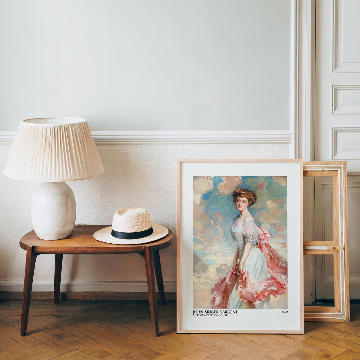 White gown portrait poster in a light wood frame leaning by a bench and hat