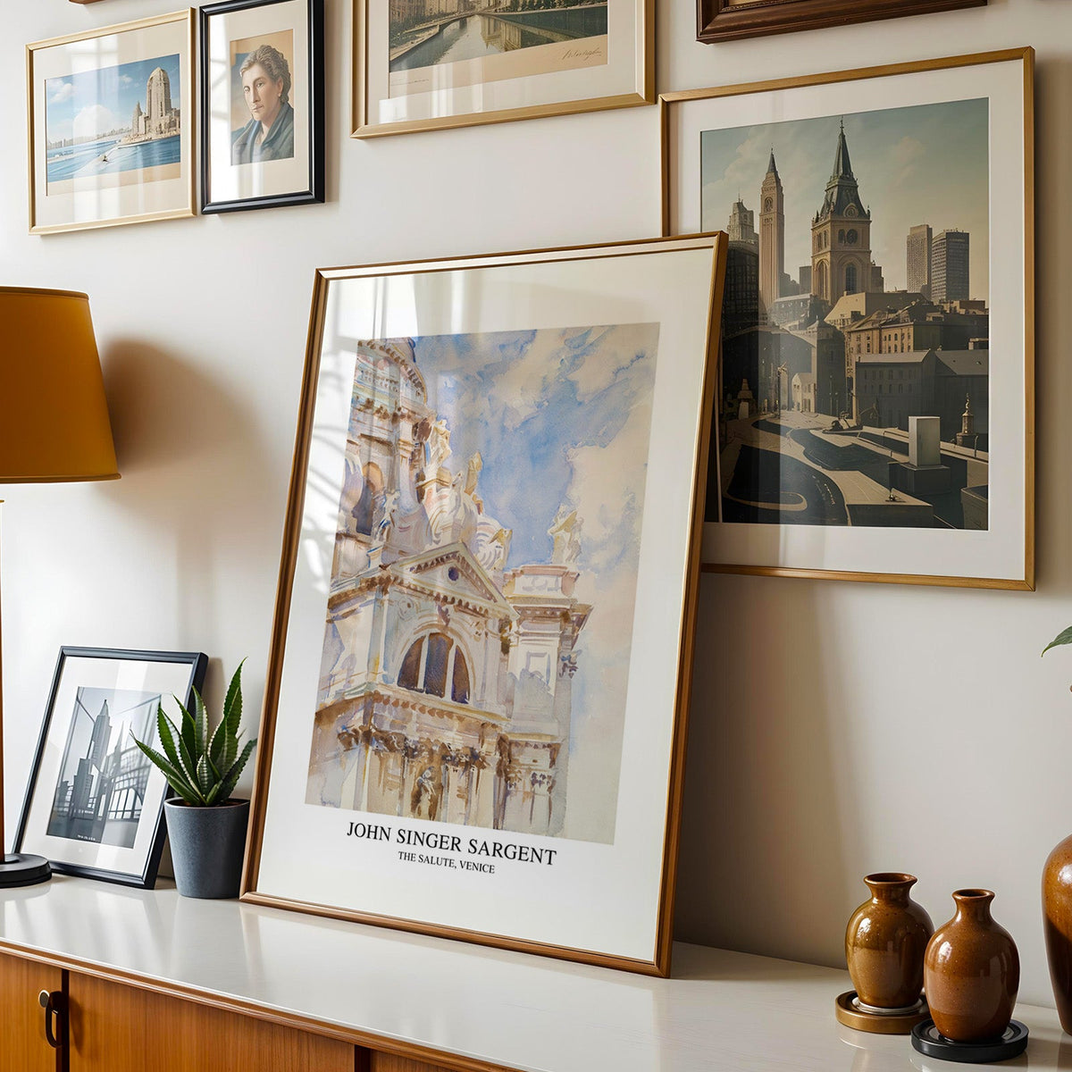 Italian architecture watercolour shown in a gold frame leaning on a sideboard in a gallery wall