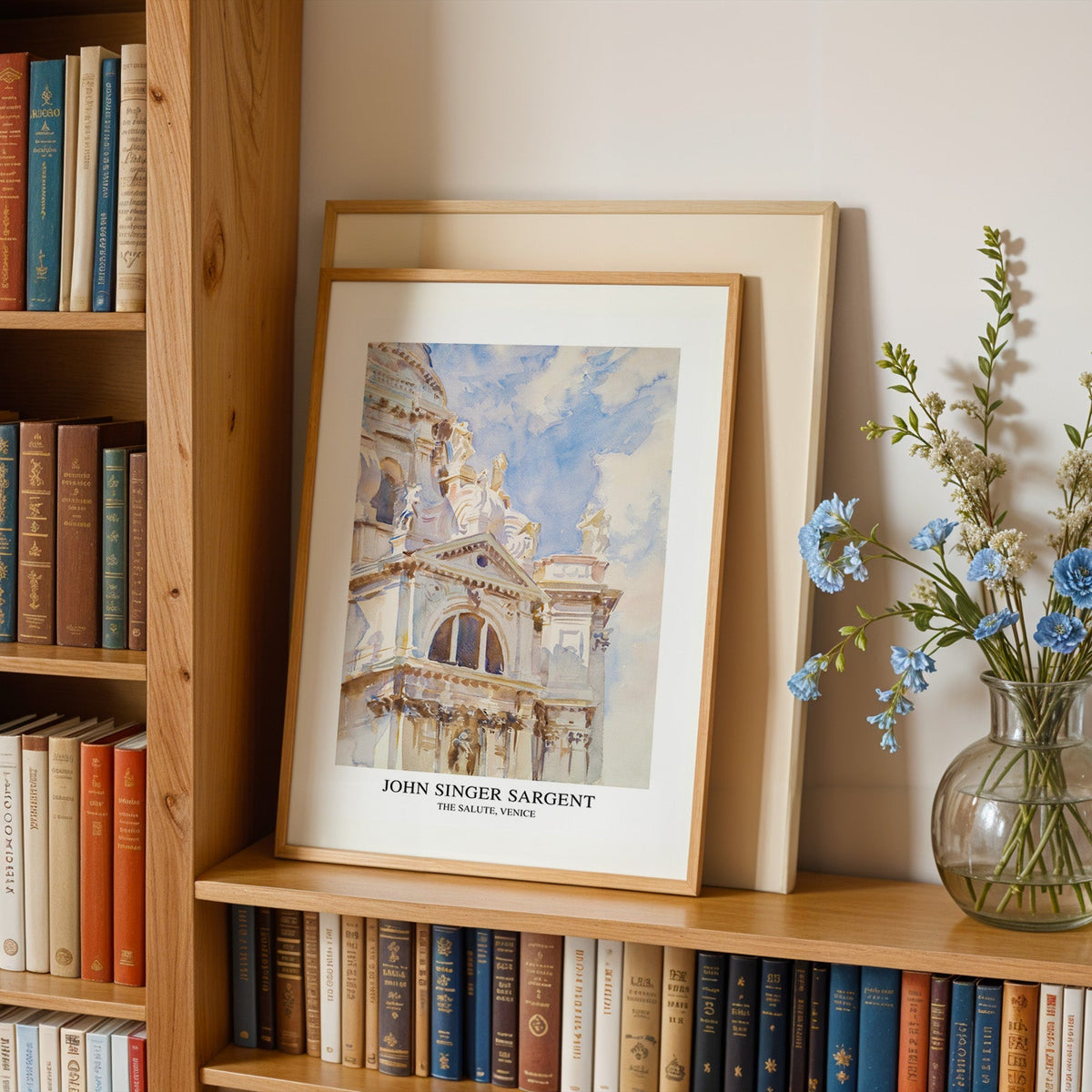 Santa Maria della Salute print in an oak frame leaning on a bookshelf beside flowers