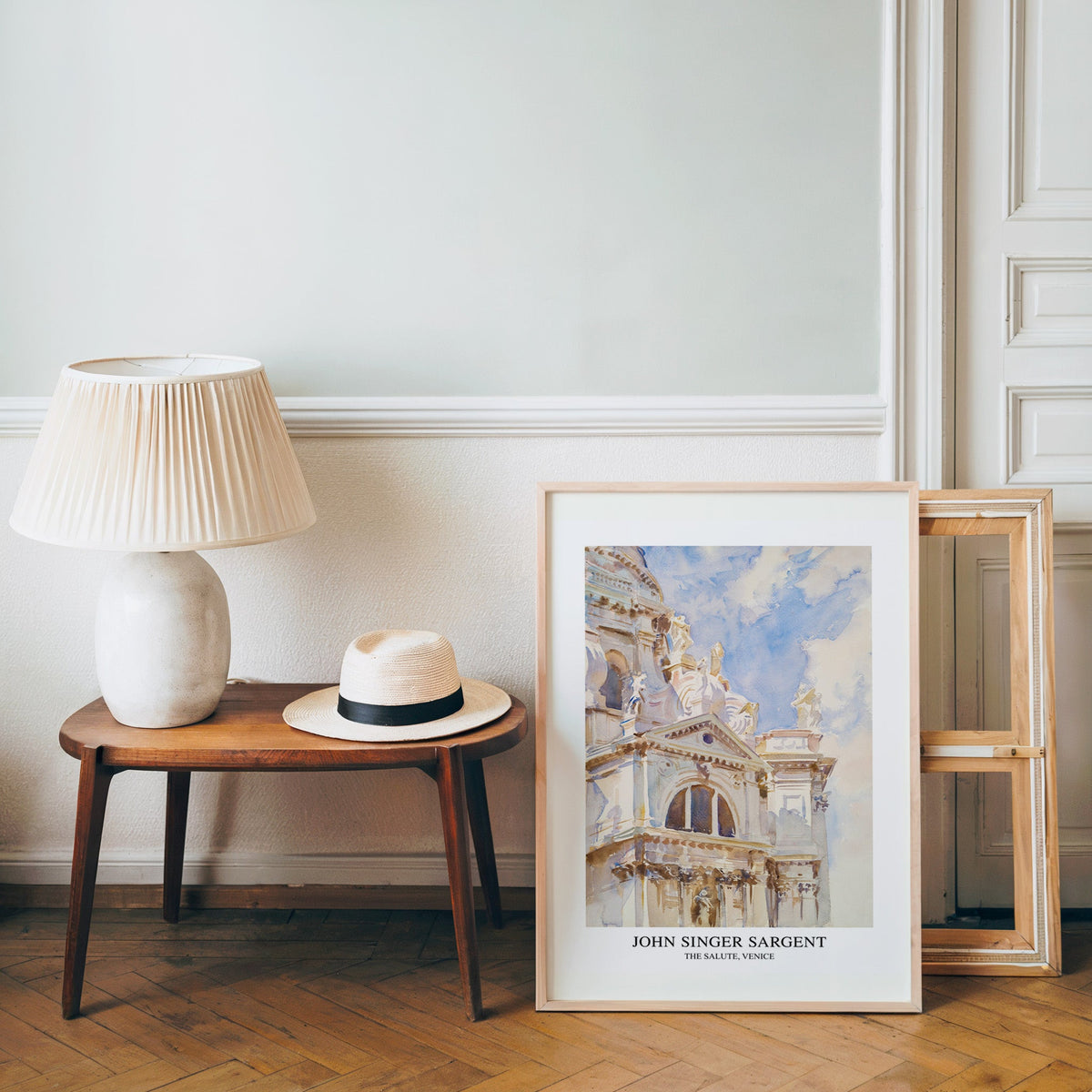 Travel watercolour poster in a light wood frame leaning by a bench and hat
