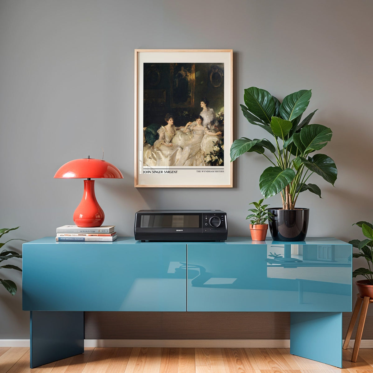 Sargent sisters print in an oak frame above a teal sideboard with a red lamp