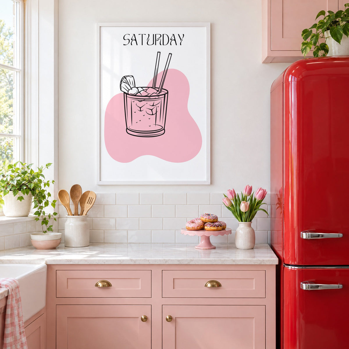 SATURDAY iced cocktail two straws print in a white frame above pink cabinets beside a red retro fridge
