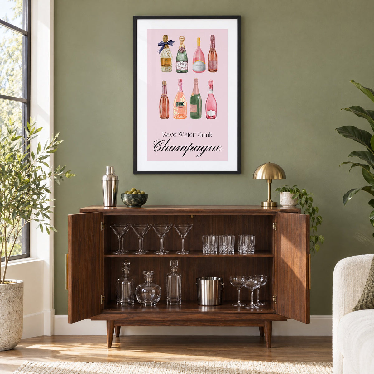 Save Water drink Champagne bottles watercolor print in a black frame on an olive green wall above a walnut bar cabinet with glassware