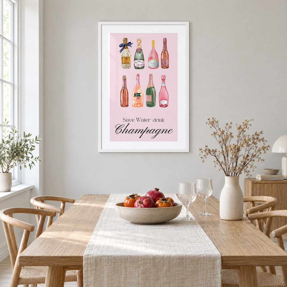 Save Water drink Champagne bottles watercolor print in a white frame above a light oak dining table with a linen runner and fruit bowl
