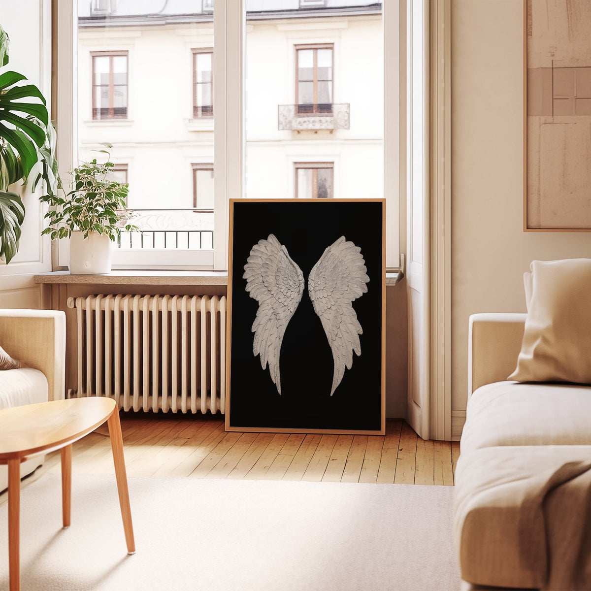 Pair of carved white angel wings on black print in an oak frame leaning by a French window in a living room