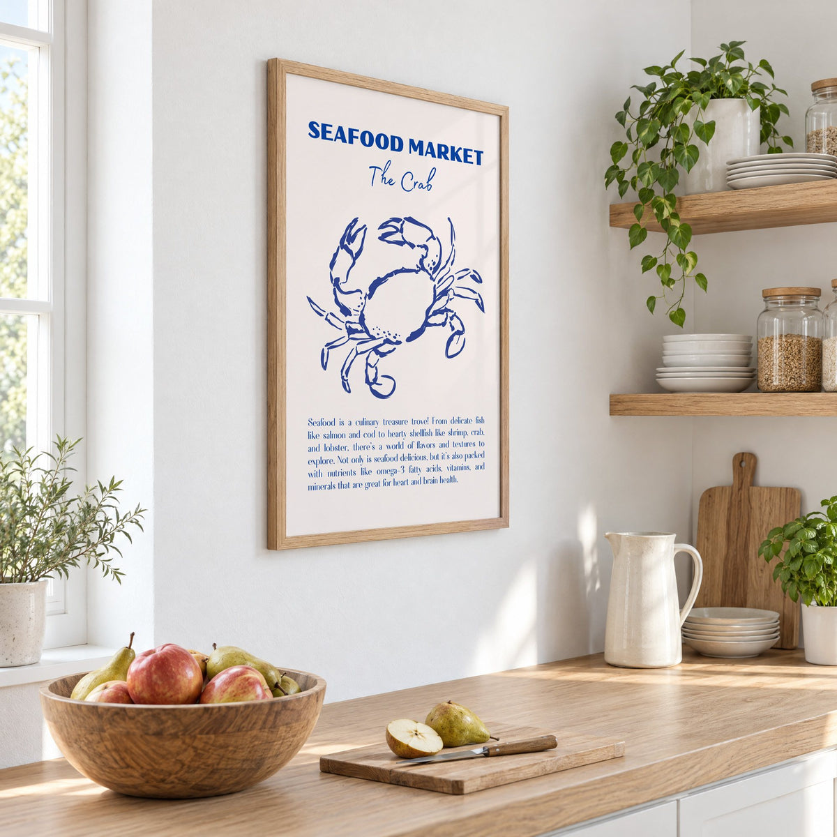 SEAFOOD MARKET The Crab cobalt sketch print in an oak frame on a white kitchen wall above a counter with apples and pears, seen at an angle