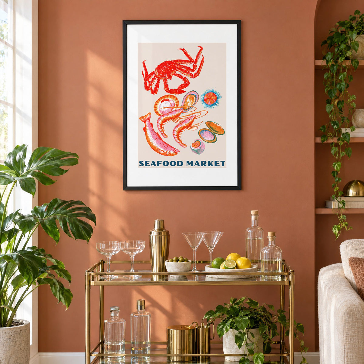 SEAFOOD MARKET gouache crab shellfish print in a black frame on a terracotta wall above a brass bar cart with coupes and citrus