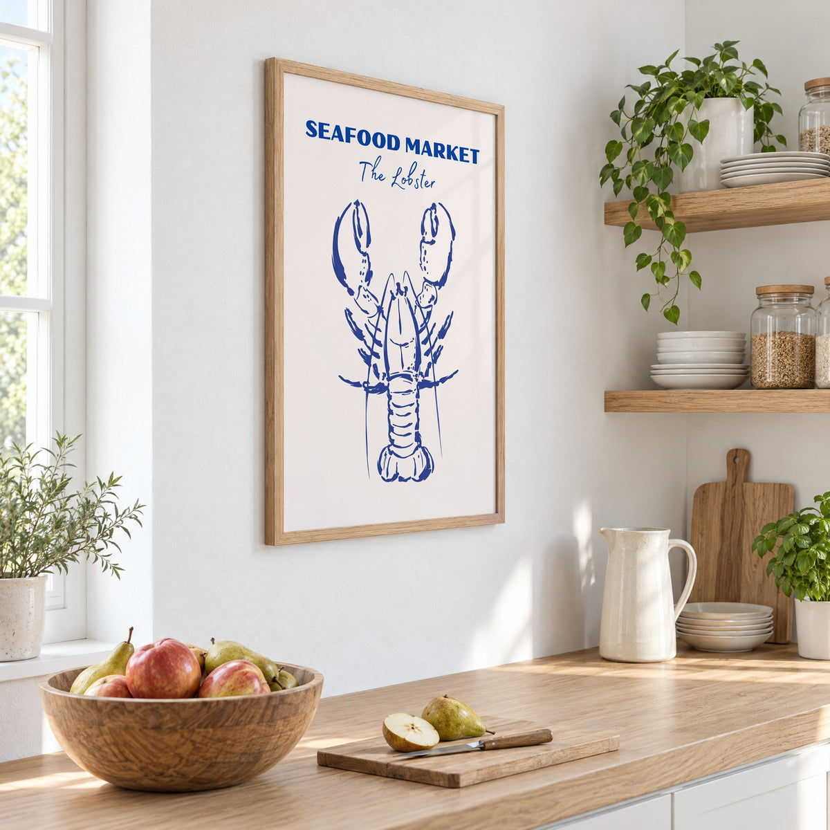 SEAFOOD MARKET The Lobster cobalt sketch print in an oak frame on a white kitchen wall above a counter with apples and pears, seen at an angle