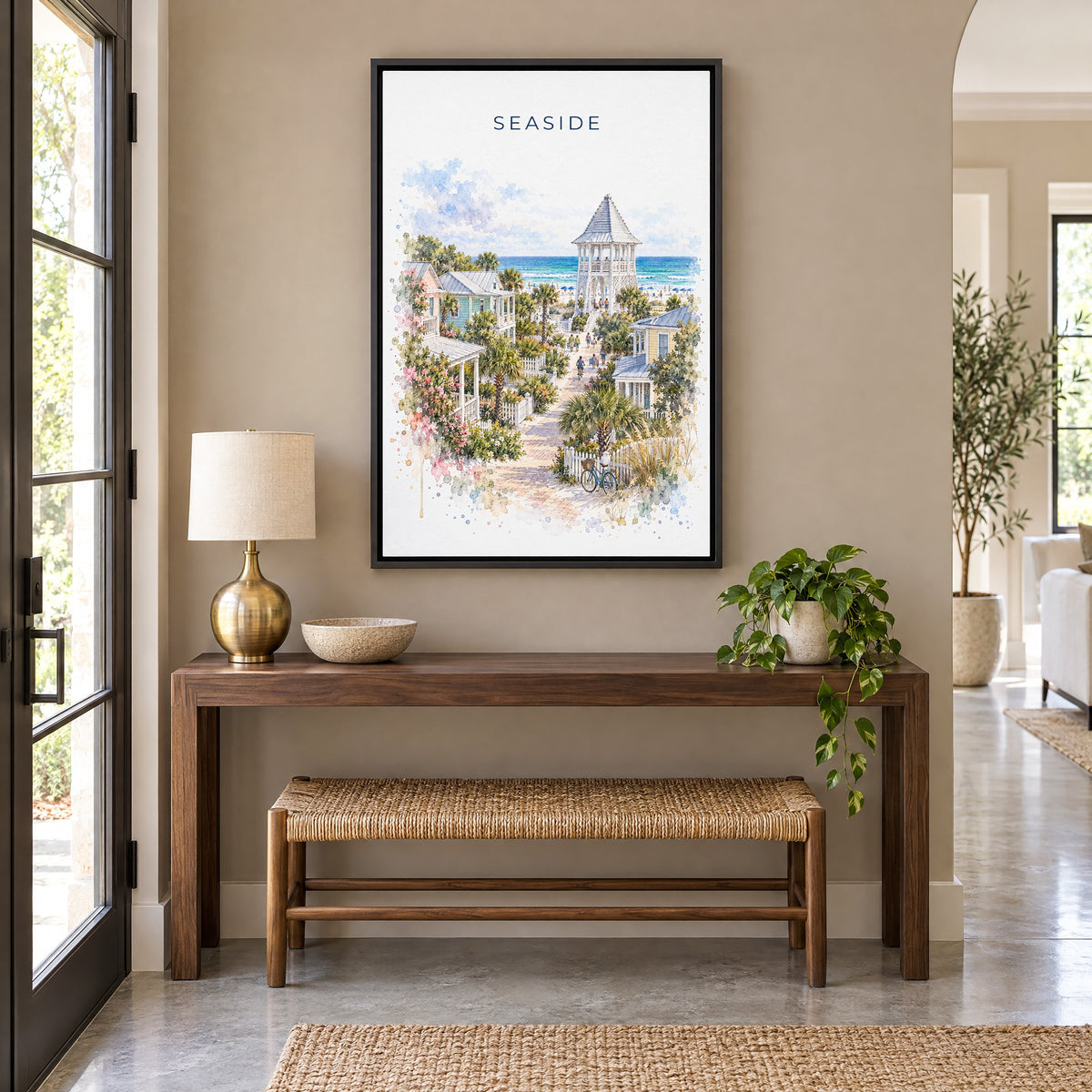 Seaside, Florida watercolor print as a black floater canvas above a walnut console and woven bench in an entryway
