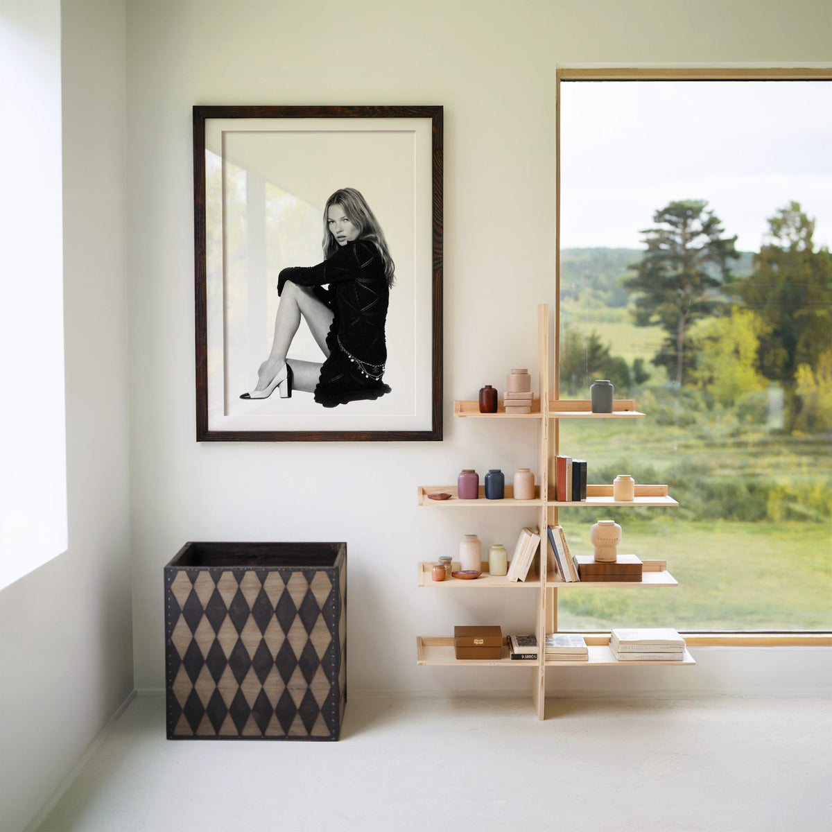 Seated woman in lace-pattern knit dress on white print in a walnut frame with a white mat beside wooden shelves and a garden window