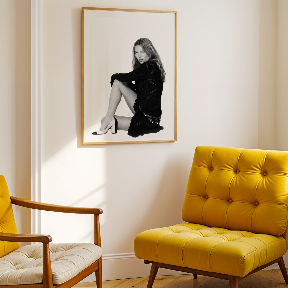 Seated woman in lace-pattern knit dress on white print shown in a gold frame above a mustard yellow tufted armchair