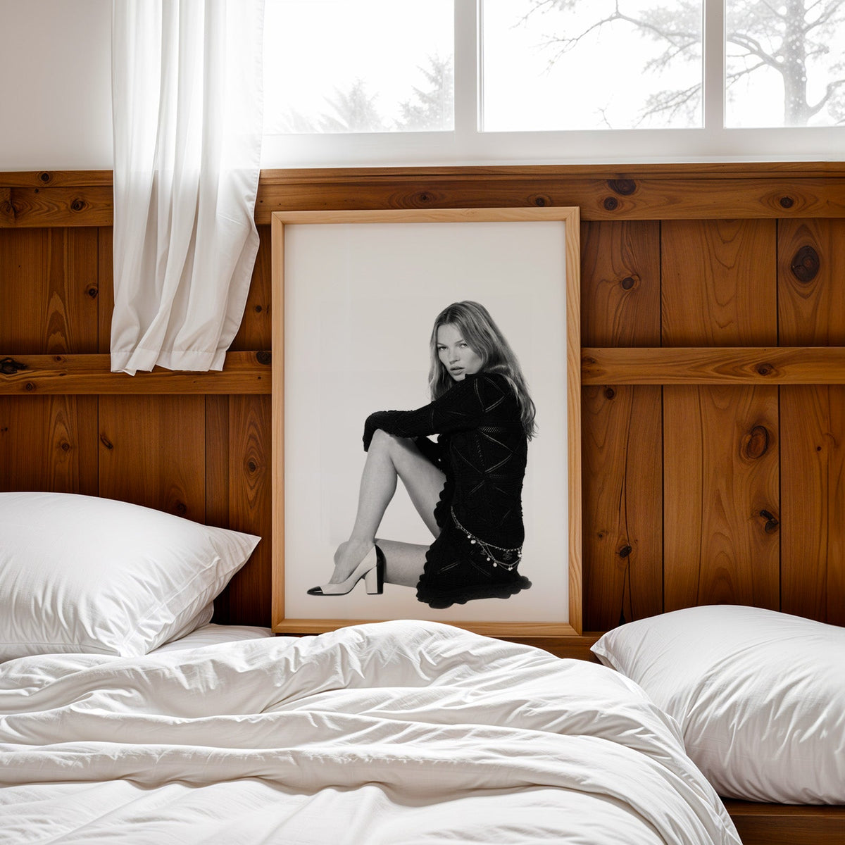 Seated woman in lace-pattern knit dress on white print in a pine frame leaning on a wood headboard over white bedding