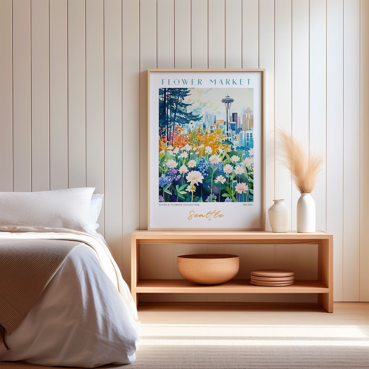 Seattle flower market print in an oak frame on a wood bench against a white shiplap bedroom wall with pampas grass