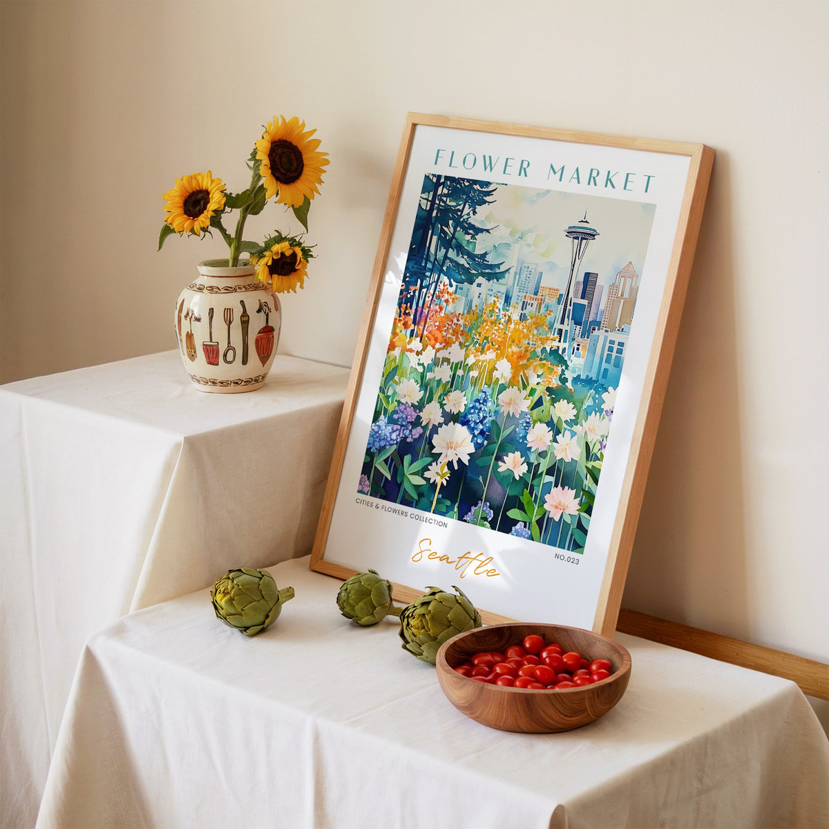 Seattle flower market print in an oak frame leaning on a linen-draped table beside a vase of sunflowers