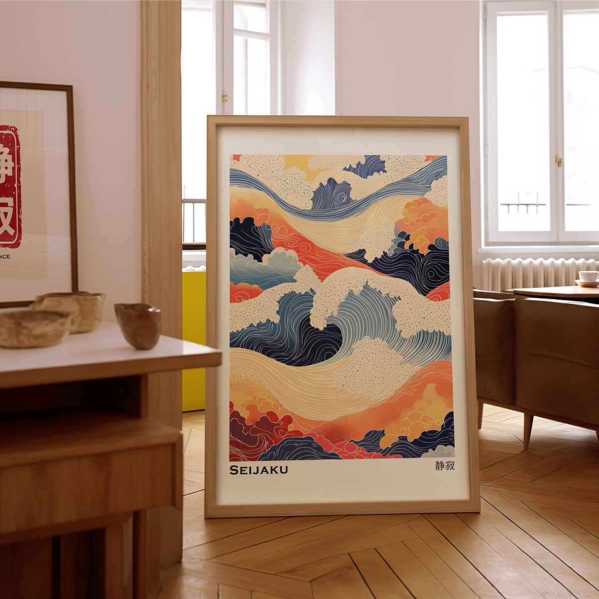 Orange and navy Seijaku waves print in an oak frame on the parquet floor of a sunlit living room
