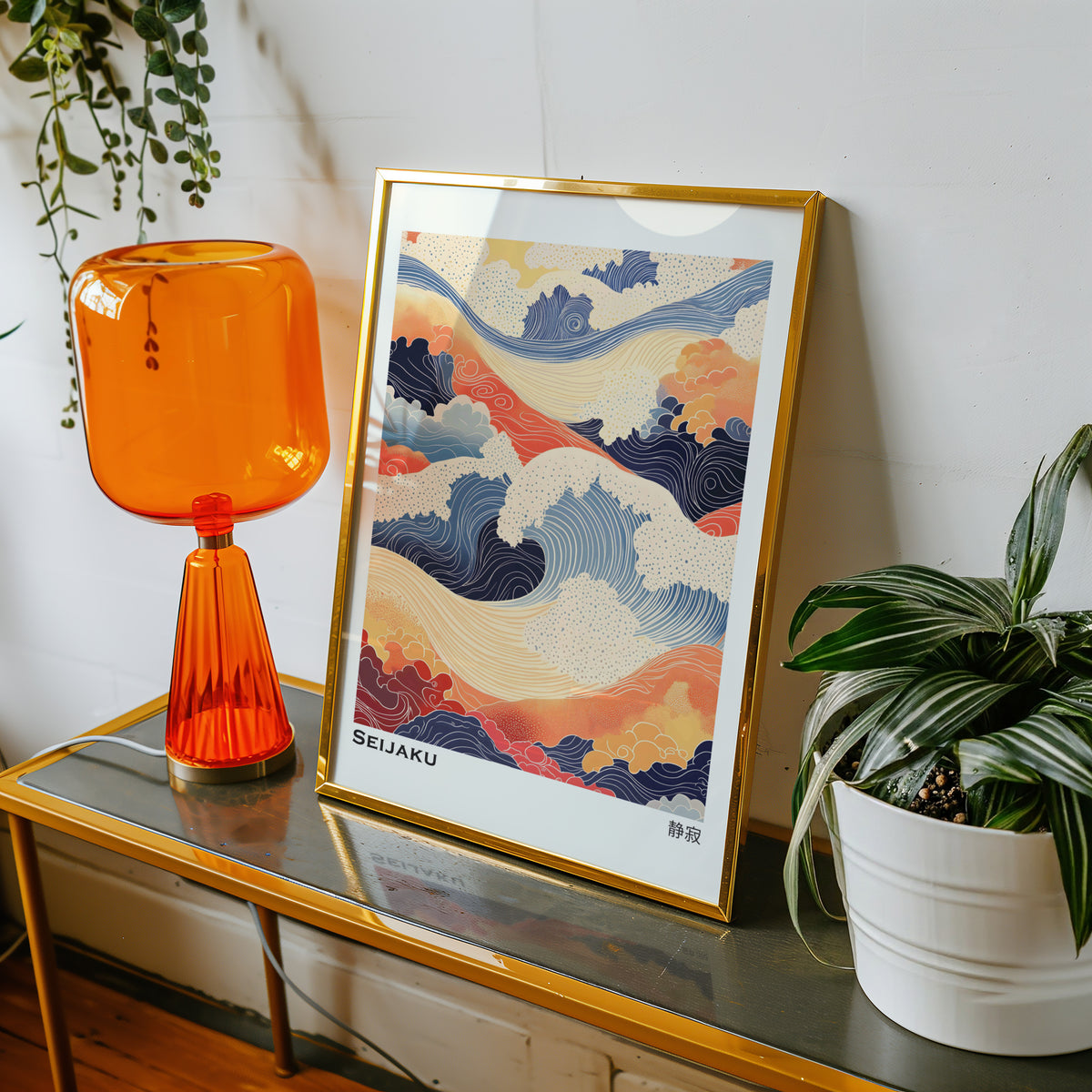 Orange and navy Seijaku waves print shown in a gold frame on a console beside an orange glass lamp