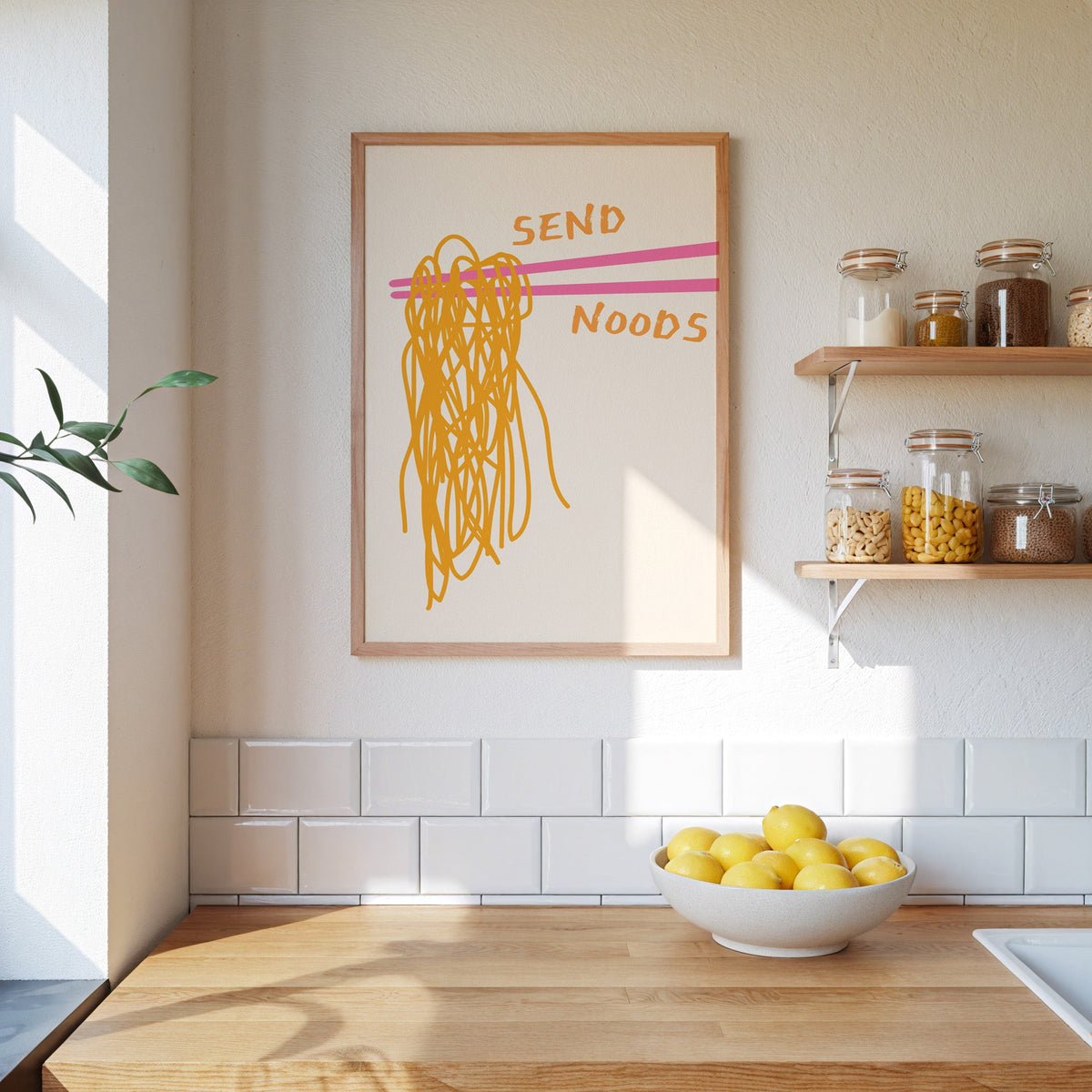 Send Noods chopsticks print in an oak frame on a subway-tiled kitchen wall beside open shelves of pantry jars