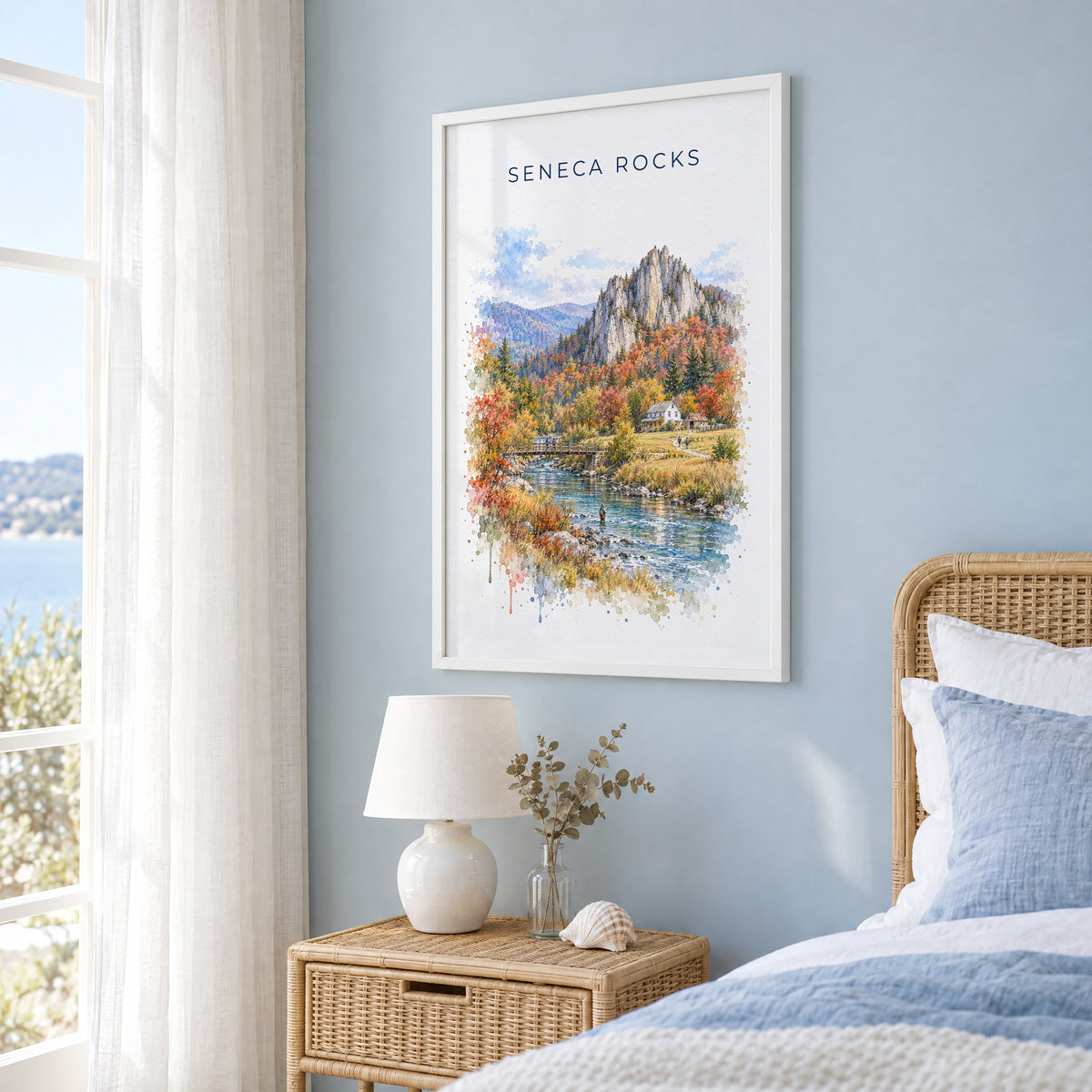 Seneca Rocks watercolor print in a white frame on a pale blue wall beside a rattan bed in a coastal bedroom