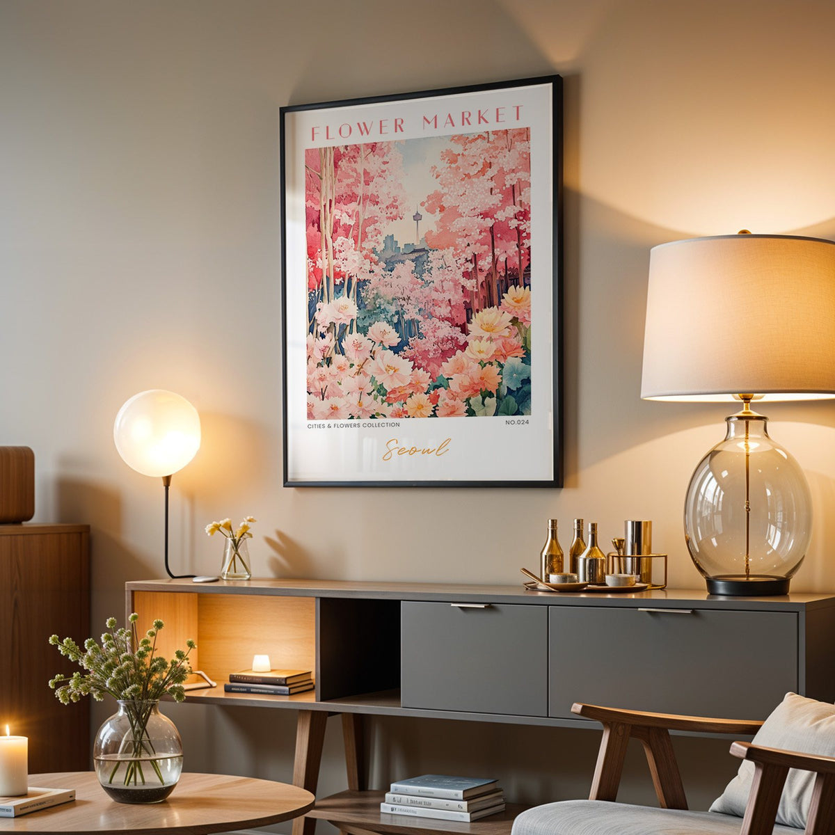 Seoul flower market print in a black frame above a grey media console with a glass table lamp