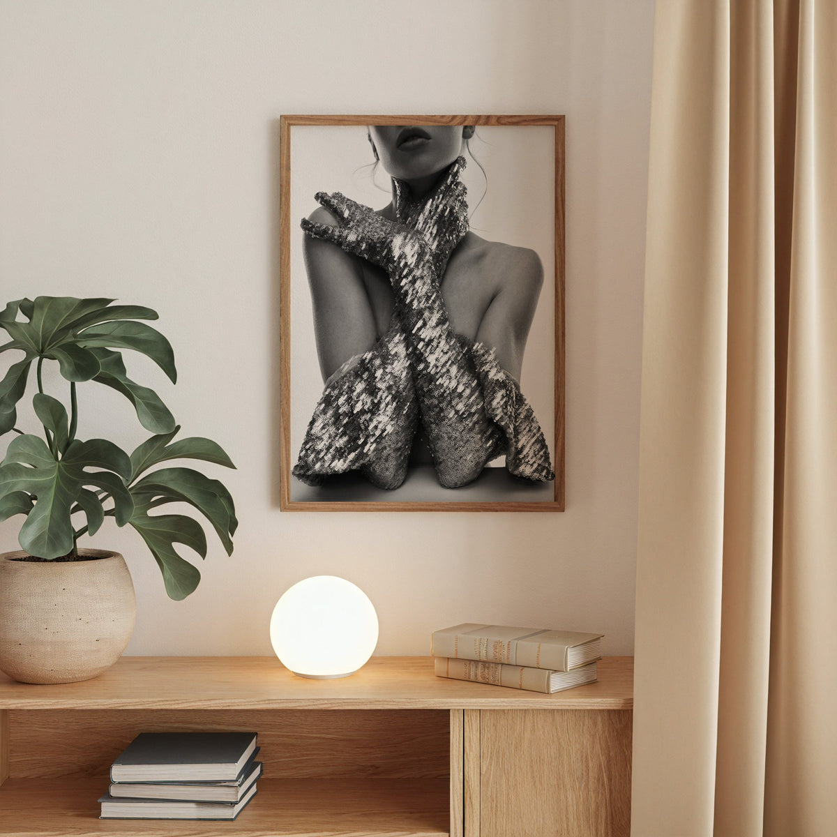Crossed arms in sequin opera gloves print in a walnut frame above an oak cabinet with a glowing globe lamp