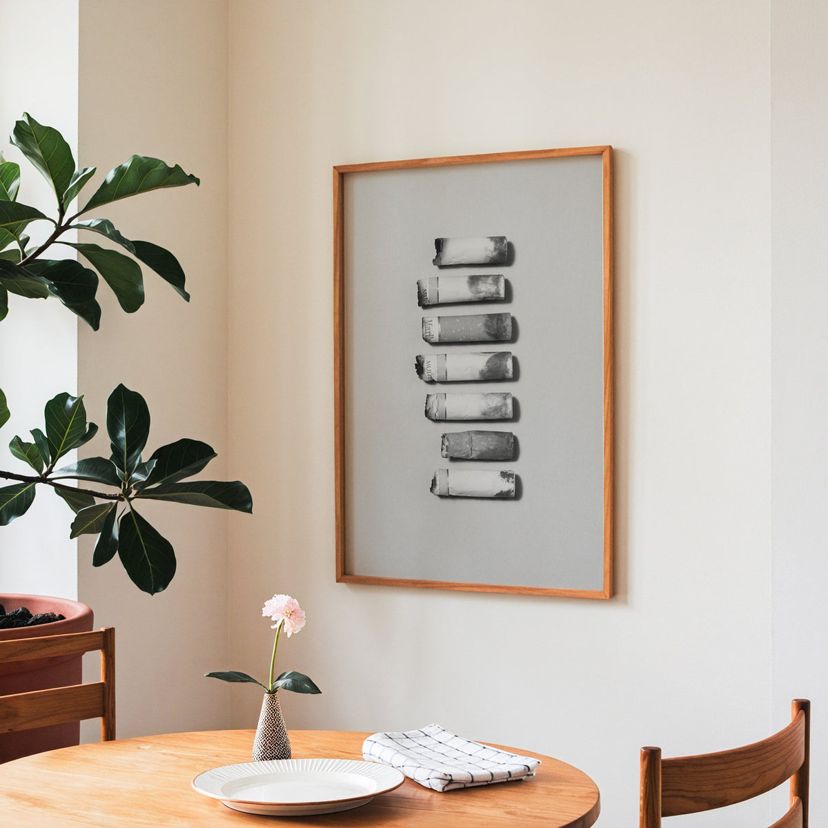 Seven cigarette ends in a column on gray print in a teak frame above a round wooden dining table