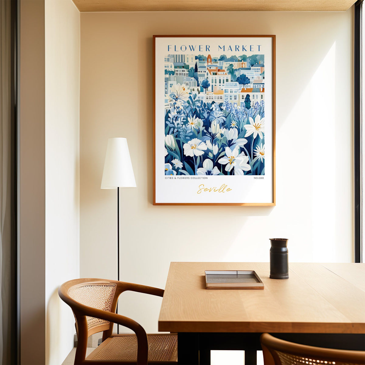 Seville flower market print in an oak frame above a dining table and cane chair