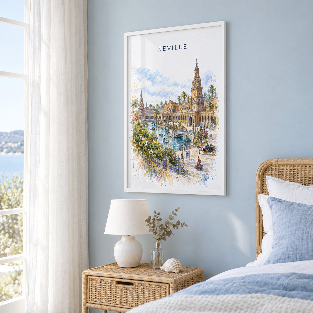 Seville watercolor print in a white frame on a pale blue wall beside a rattan bed in a coastal bedroom
