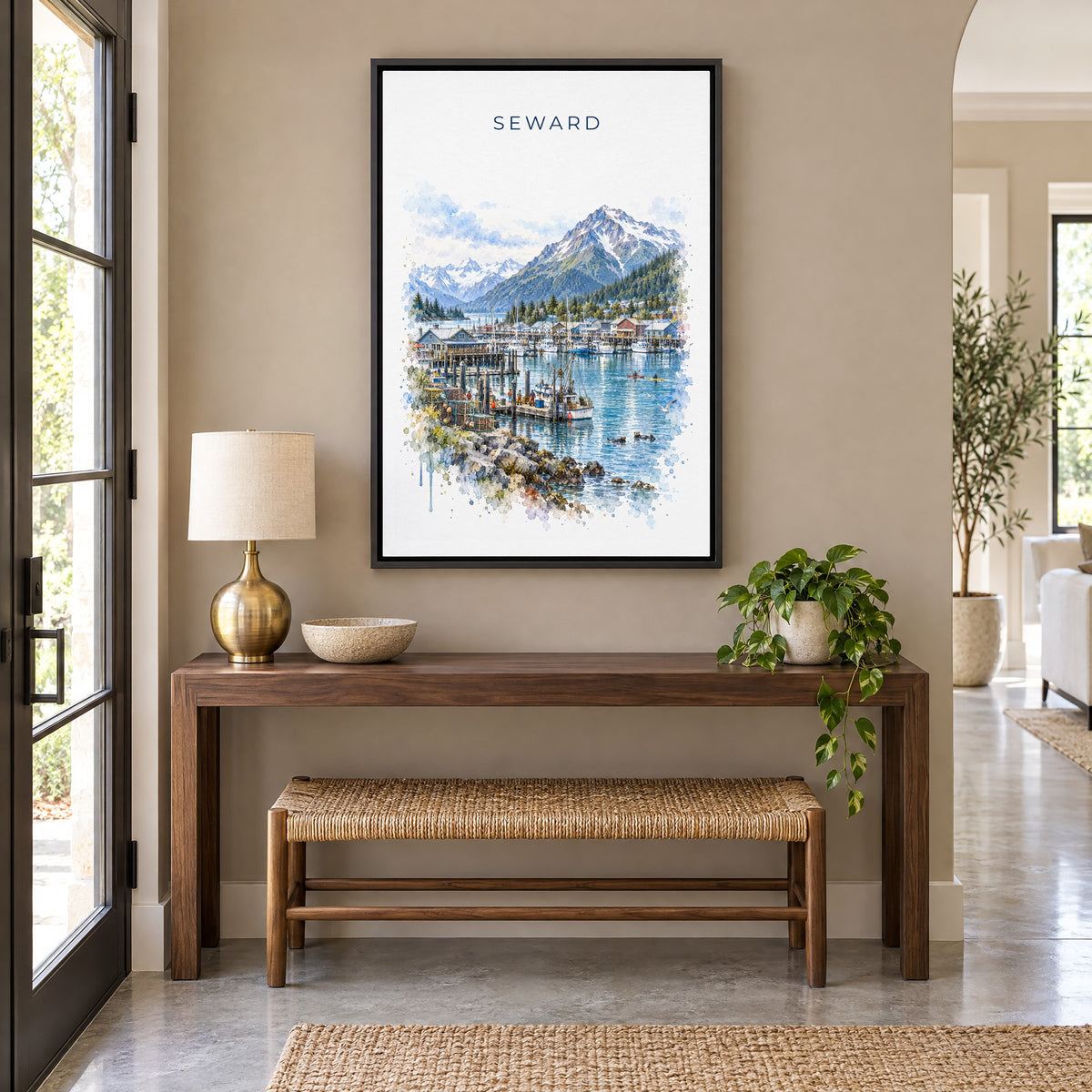 Seward, Alaska watercolor print as a black floater canvas above a walnut console and woven bench in an entryway