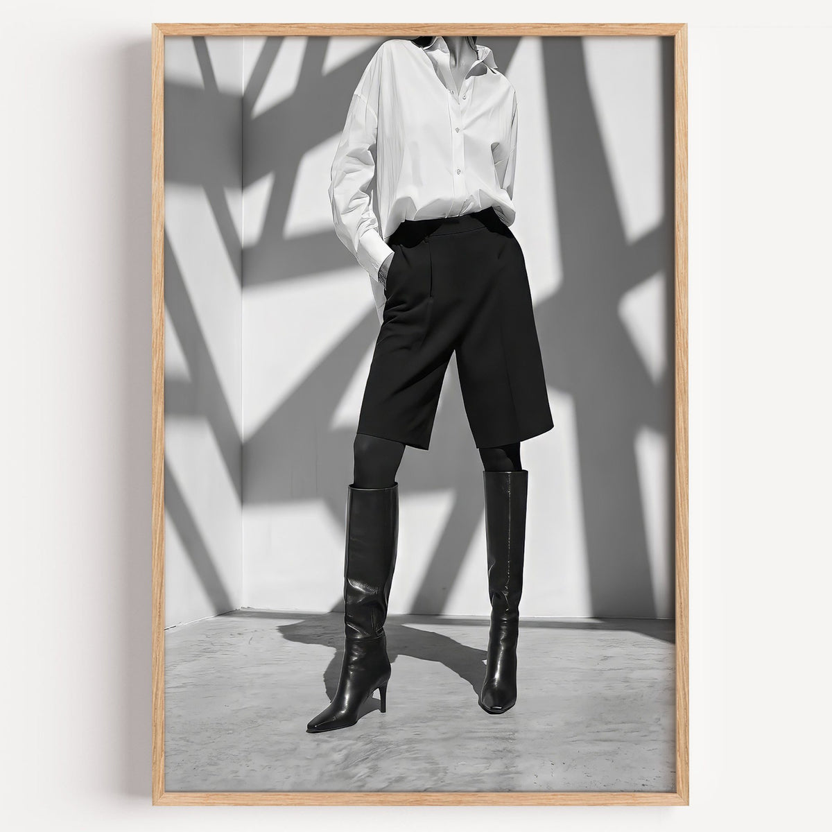 Black and white shirt and knee boots shadow wall print in a light oak frame on a plain white wall