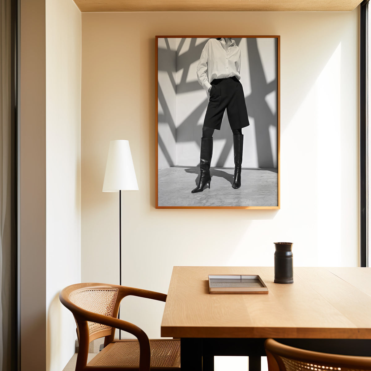Black and white shirt and knee boots shadow wall print in an oak frame above a dining table and cane chair