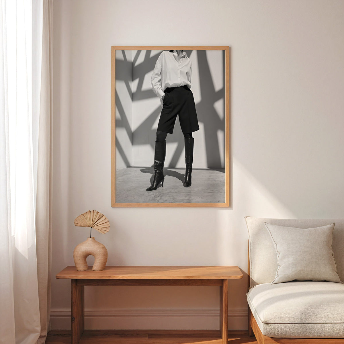 Black and white shirt and knee boots shadow wall print in an oak frame above a narrow console with an arched vase