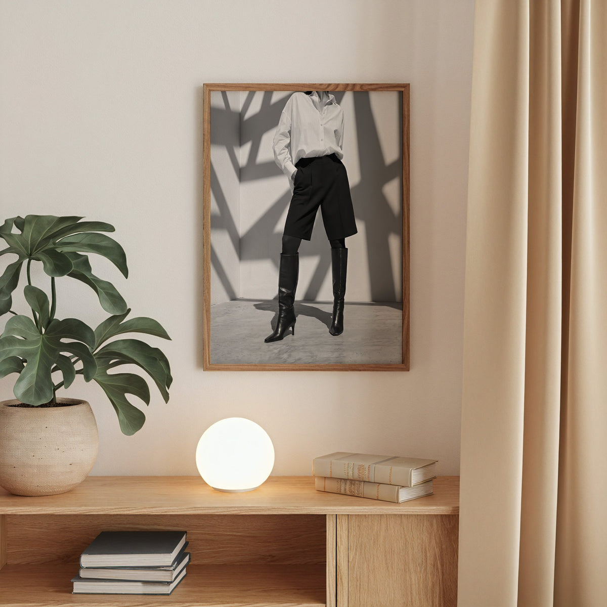 Black and white shirt and knee boots shadow wall print in a walnut frame above an oak cabinet with a glowing globe lamp