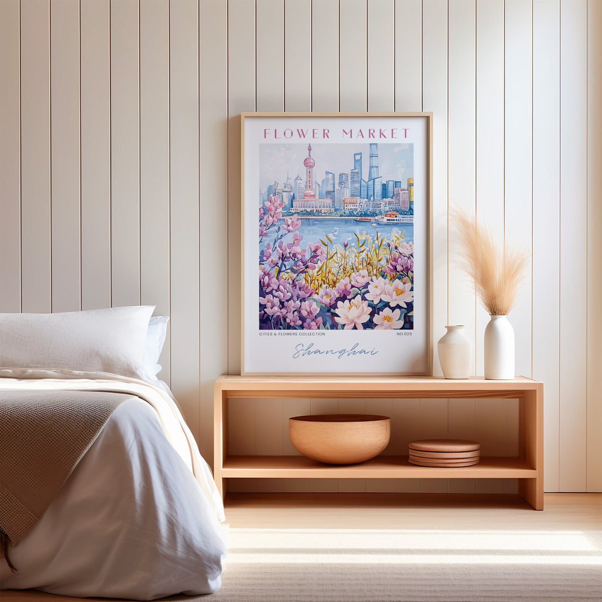 Shanghai flower market print in an oak frame on a wood bench against a white shiplap bedroom wall with pampas grass