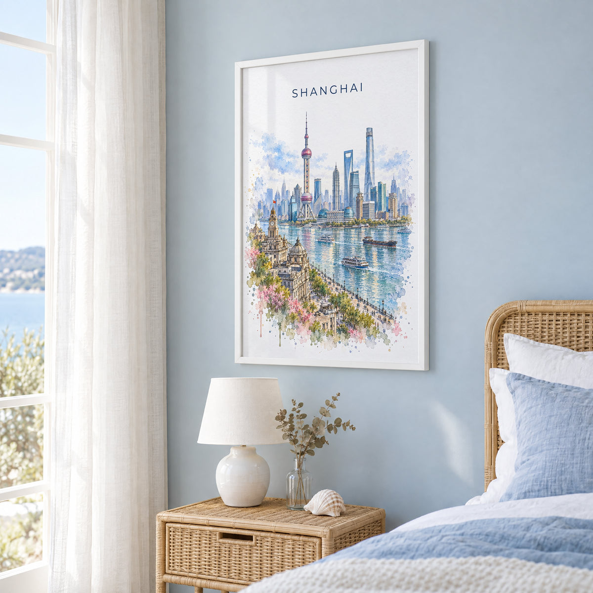 Shanghai watercolor print in a white frame on a pale blue wall beside a rattan bed in a coastal bedroom
