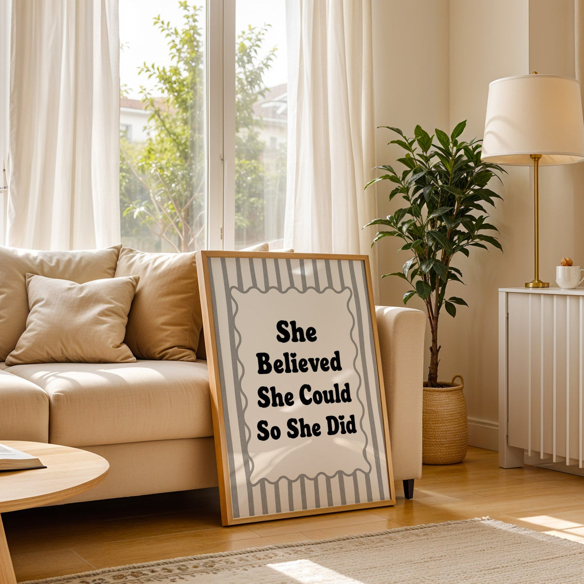 She believed she could so she did striped quote print in a light oak frame leaning on a cream sofa beside a floor lamp