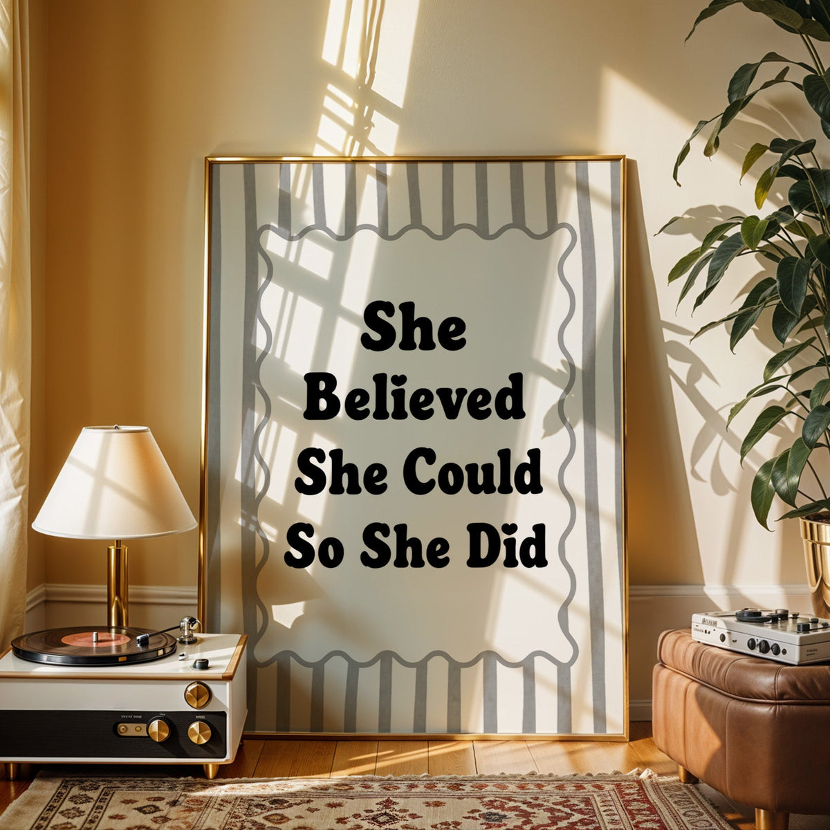 She believed she could so she did striped quote print shown in a gold frame beside a record player and table lamp