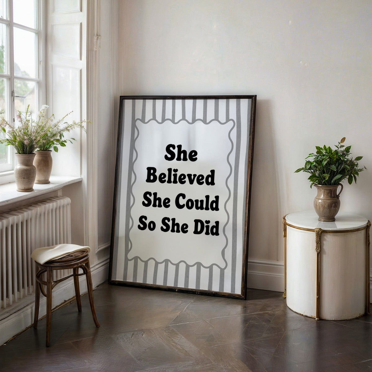She believed she could so she did striped quote print in a black frame on a dark stone floor beside a white side table