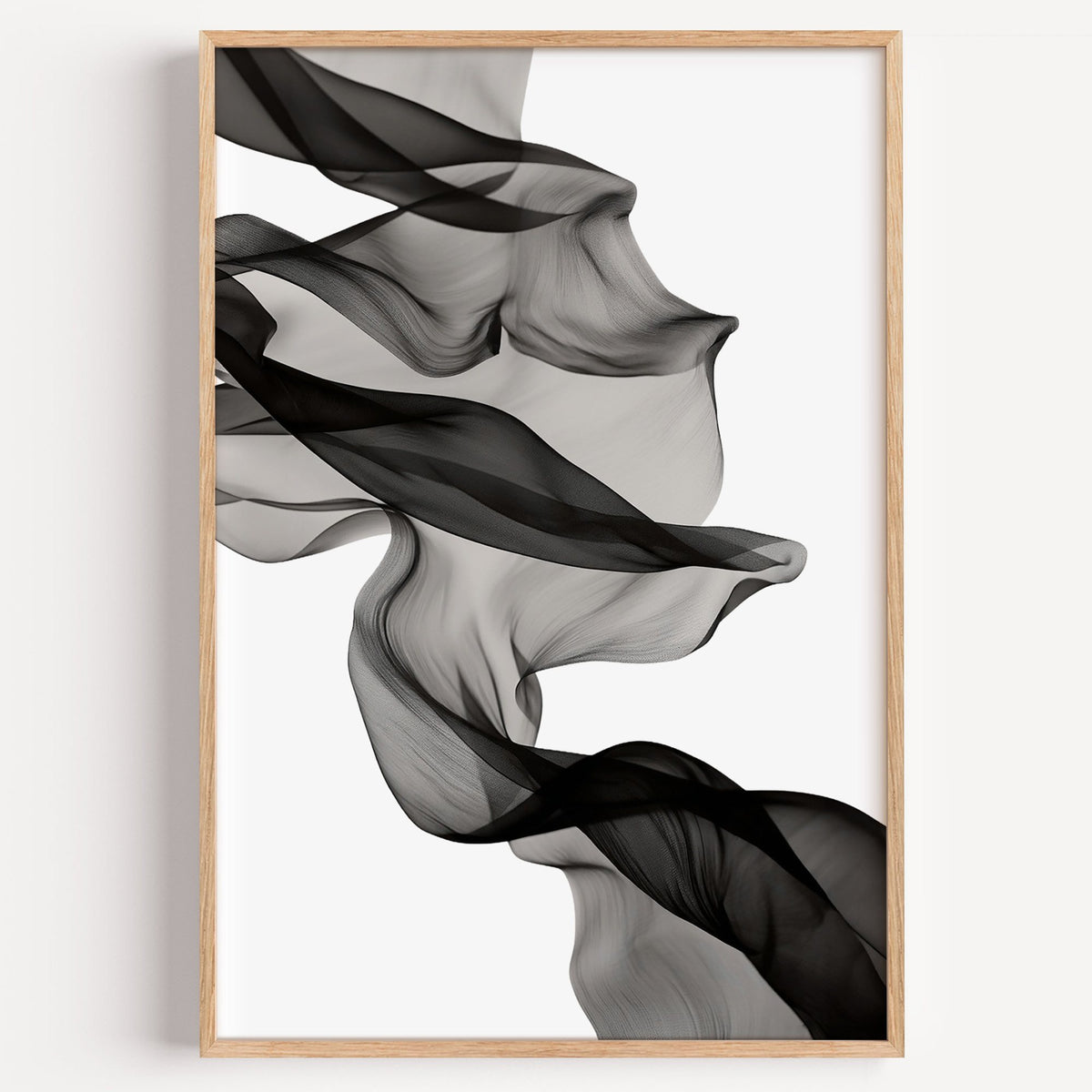 Sheer black fabric flowing across white print in a light oak frame on a plain white wall