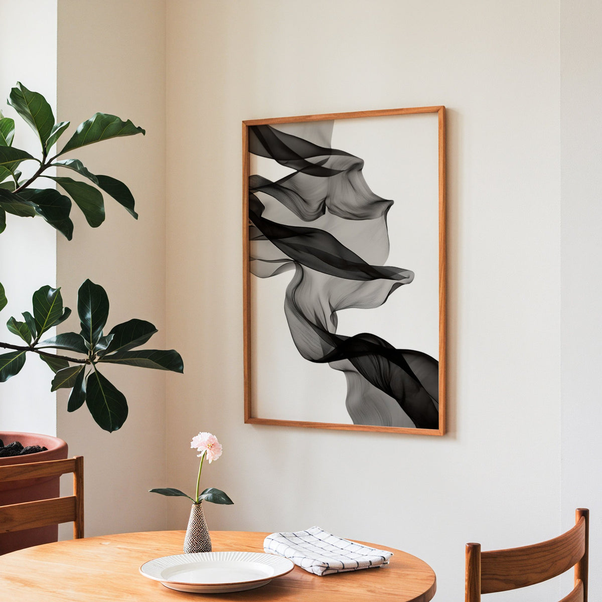Sheer black fabric flowing across white print in a teak frame above a round wooden dining table