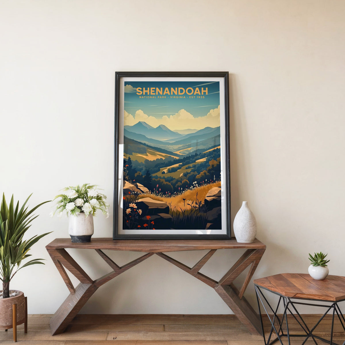 Shenandoah poster in a black frame on an entryway console table beside white flowers and a yucca