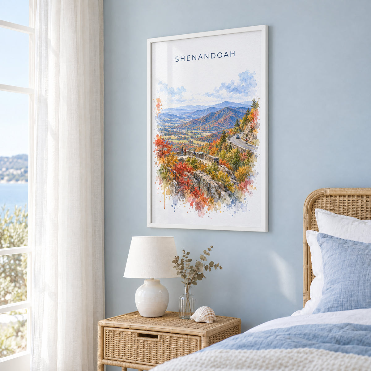 Shenandoah National Park watercolor print in a white frame on a pale blue wall beside a rattan bed in a coastal bedroom