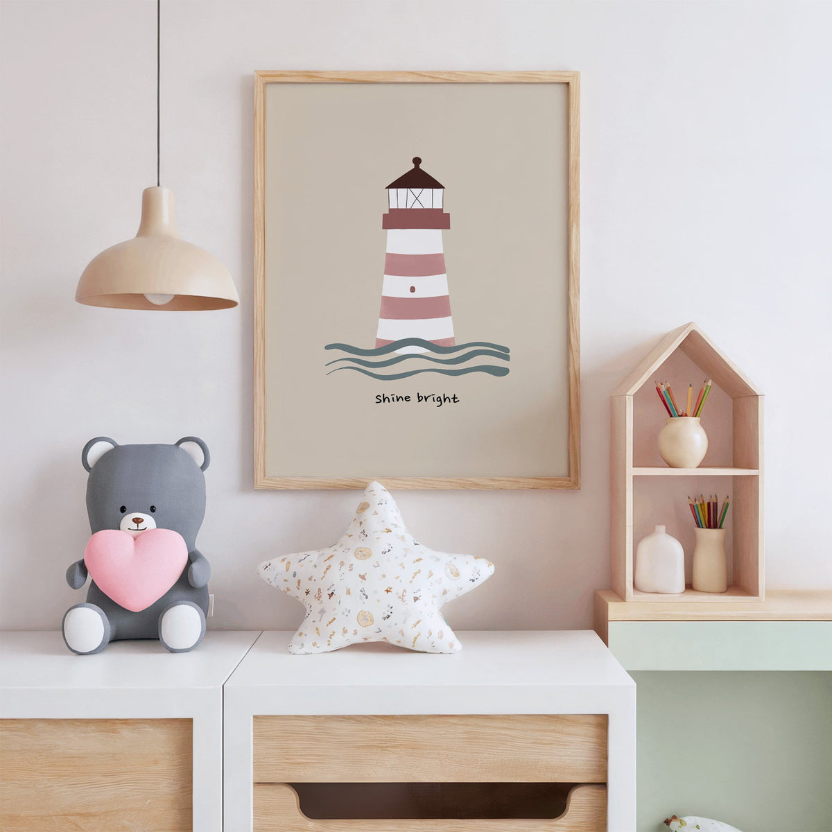 Shine bright lighthouse nursery print in an oak frame above a white dresser with a star pillow and house shelf