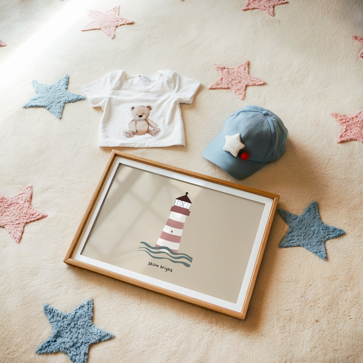 Landscape shine bright lighthouse nursery print in a matted oak frame on a star rug with a baby tee